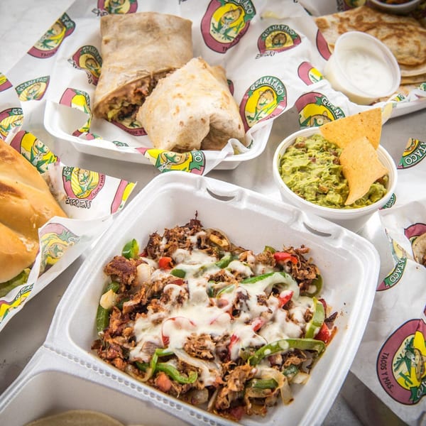 A spread of Guanataco Mexican food, including burritos, fajitas, guacamole, and quesadillas.