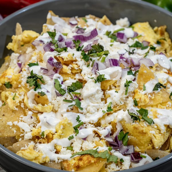Close-up of Guanataco's chilaquiles with scrambled eggs, cheese, red onion, and cilantro.