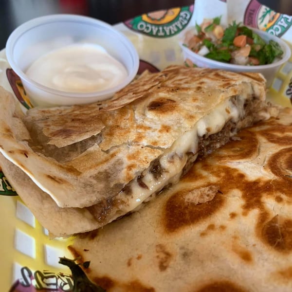 A Guanataco quesadilla with melted cheese and meat, served with sour cream and salsa.