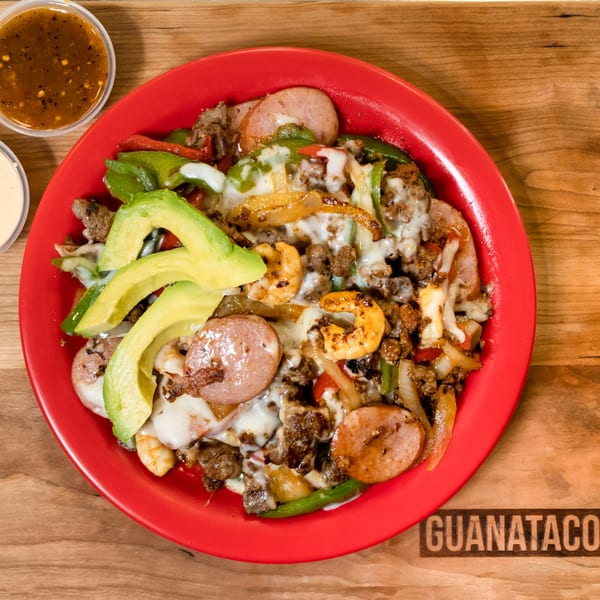 Guanataco's mixed fajita plate with steak, shrimp, sausage, avocado, and melted cheese.