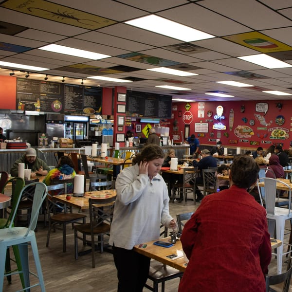 A bustling Guanataco Mexican restaurant interior with patrons dining at tables and colorful decor.